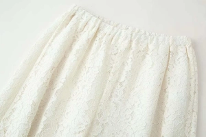 Detailed macro view of the elastic waistband on white floral lace wide leg trousers