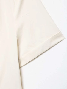 Detail of short sleeves on cream cropped shirt showing smooth fabric and neat stitching