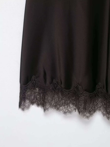 Détail de l'ourlet de jupe en satin noir avec dentelle de cils délicate et texture soie