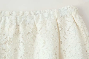 Detail of white floral lace fabric with elastic pleated waistband and hollow texture