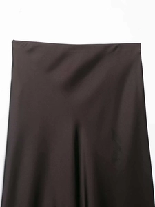 Détail de la jupe midi en satin marron chocolat montrant la texture soyeuse et brillante