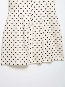 Detailansicht eines cremefarbenen Sommerkleids mit klassischem schwarzem Polka-Dot-Muster