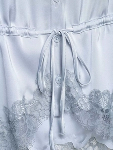 Close-up of light blue satin fabric with drawstring waist and delicate lace hem detail