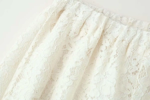Detailed macro view of white floral lace fabric and pleated hemline textures