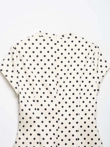 Detail eines weißen Polka-Dot-Kleides mit Reißverschluss hinten und kleinem Stehkragen