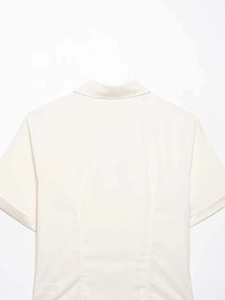 Detailed close-up showing the collar and tailored shoulder seams of the cream pleated shirt