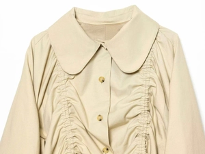 Detail of apricot Peter Pan collar jacket with drawstring pleats and mottled buttons