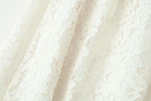 Macro shot of white intricate floral lace fabric with hollow-out leaf patterns and texture