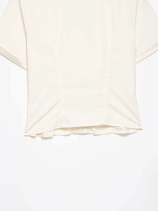 Close-up of beige cropped shirt showing textured fabric and delicate pleated waist details