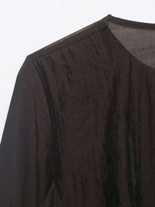 Detail of sheer chiffon fabric texture and neckline stitching on a dark ruffled top
