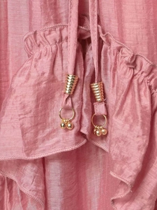 Detail of pink ruffled fabric with vertical texture and gold conical drawstring tips