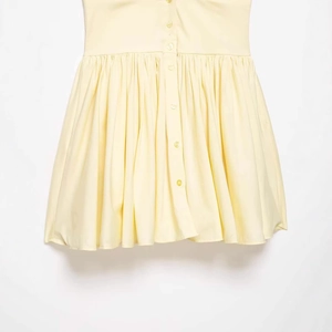 Pale yellow sleeveless pleated dress featuring a button-down front for a summer look