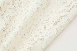 Detailed close-up showing intricate floral lace patterns on cream wide-leg pants fabric
