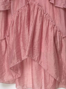 Detail view of pink ruffled fabric showing layered soft texture and flowing draped material