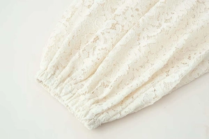Close-up of white floral hollow lace fabric with elastic pleated cuffs on loose pants