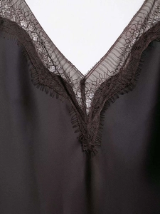 Detail of V-neckline with black satin fabric and brown eyelash lace trim on dress