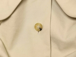 Detail shot of the beige doll collar jacket showing twill fabric and amber button