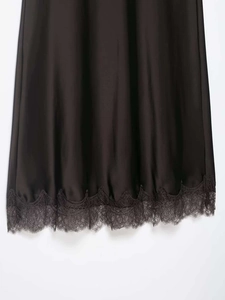 Détail d'une jupe en satin noir avec ourlet en dentelle délicate et finition lisse
