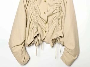 Detail of apricot doll collar jacket with drawstring pleats and textured buttons