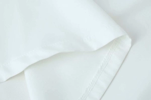Detailed macro view of high-quality stitching and seaming on white pleated dress fabric