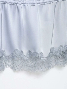 Detail of light blue satin camisole with elastic waist and eyelash lace hemline trim