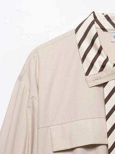 Detail of beige shirt showing striped collar, matching tie, and a front chest pocket
