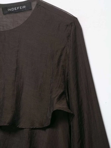 Close-up of ruffled chiffon blouse with pleated texture and brand label on the neckline