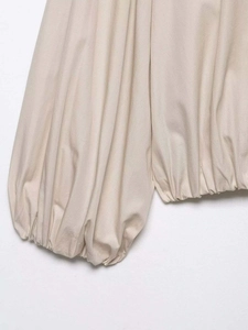 Detail view of apricot striped shirt showing puff sleeve and elastic smocked hem texture