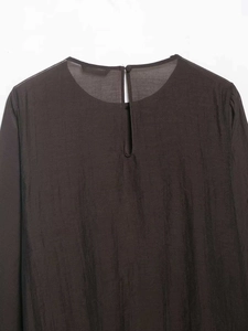 Detail of the back keyhole closure and pleated texture on a dark chiffon blouse