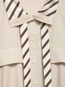 Detail view of beige striped shirt featuring a brown contrast collar and tie accessory