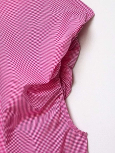 Close-up of pink and white gingham fabric showing detailed pleats and fine stitching