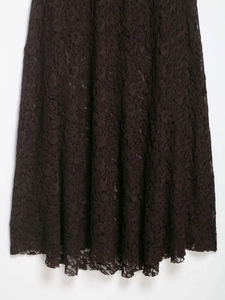 Détail de l'ourlet de robe en dentelle marron foncé avec motifs floraux ajourés
