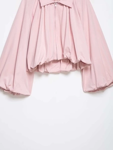 Detail of light pink bomber jacket featuring voluminous puff sleeves and metallic zipper