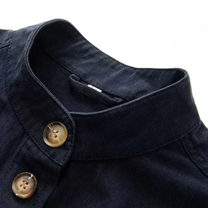 Detailed close-up of amber buttons and stand collar on navy blue denim jacket