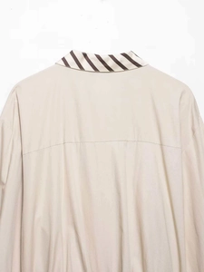 Detailed view of apricot shirt collar with dark brown striped tie-back ribbon detail
