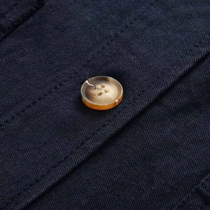 Close-up of a brown marble-pattern button on dark blue twill denim jacket fabric