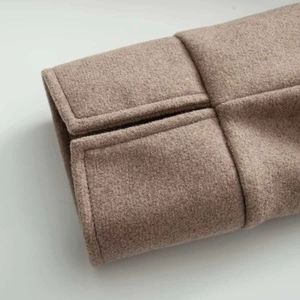 Detail of light brown wool coat sleeve with handcrafted pick stitching and slit cuff design