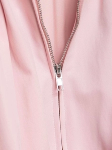 Detailed macro view of the silver metal zipper on the light pink bomber jacket fabric