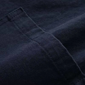 Detail of neat stitching on dark navy denim jacket pocket with visible twill fabric texture