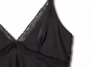 Detailed view of black satin camisole featuring delicate eyelash lace trim and V-neckline