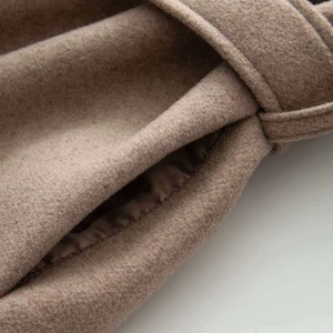 Detail of wool coat fabric featuring deep brown texture, side pocket and belt loop