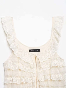 Détail des volants en dentelle et du col noué sur ce débardeur blanc crème chic