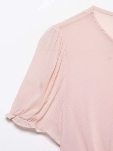 Detail of light pink puff sleeves with delicate pleats on a V-neck chiffon blouse
