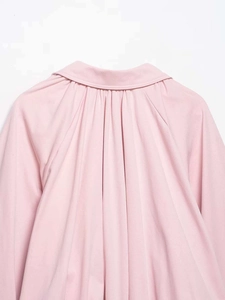 Detail of light pink jacket showing pleated back design and soft textured fabric finish