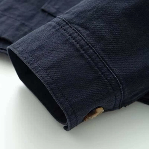 Detailed close-up of dark blue denim jacket cuff with vintage brown button and stitching