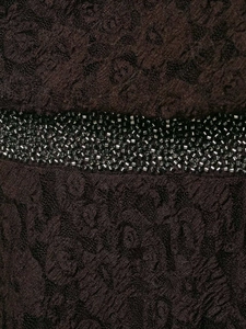 Détail du tissu en dentelle foncée avec motifs floraux et broderies de perles noires denses