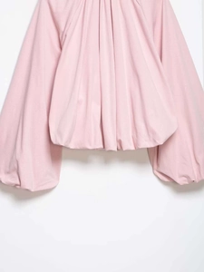 Close-up detail of pink bomber jacket with pleated texture and voluminous bubble sleeves