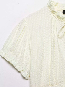 Detail of cream puff sleeve blouse featuring ruffled neckline and seersucker texture