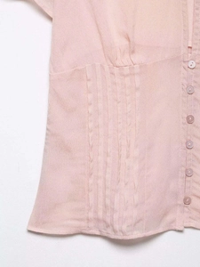 Detail view of pink chiffon blouse featuring vertical pleats and single-breasted buttons