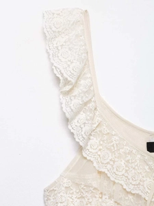 Détail de la bordure en dentelle florale crème et texture plissée sur un caraco d'un caraco d'été